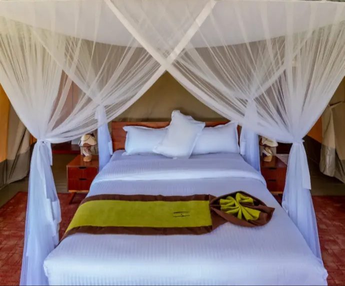 Canopy bed under mosquito netting in a tented camp